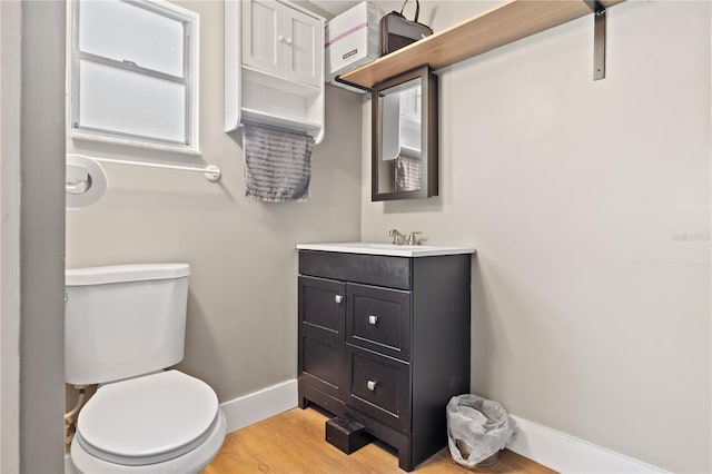 bathroom with vanity, toilet, wood finished floors, and baseboards