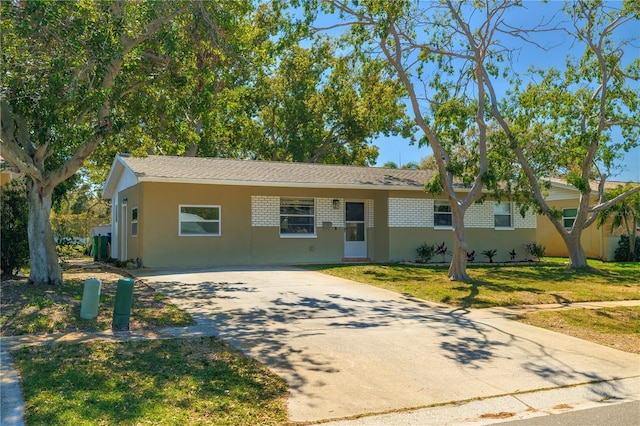 single story home featuring brick siding, concrete driveway, and a front yard