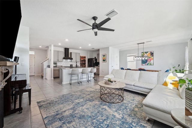 living room featuring visible vents, ceiling fan with notable chandelier, recessed lighting, light tile patterned flooring, and baseboards