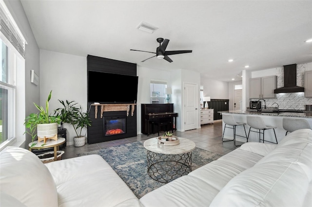 tiled living area featuring a glass covered fireplace, a healthy amount of sunlight, and visible vents