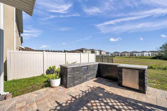 view of patio with a fenced backyard, a residential view, and an outdoor kitchen