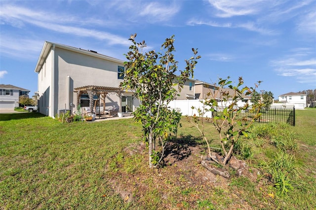 rear view of property with a yard, a patio, stucco siding, and a pergola