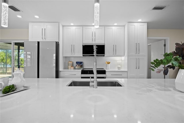 2008 41st St W, Bradenton, FL 34205 - kitchen featuring white cabinets, visible vents, freestanding refrigerator, and a sink