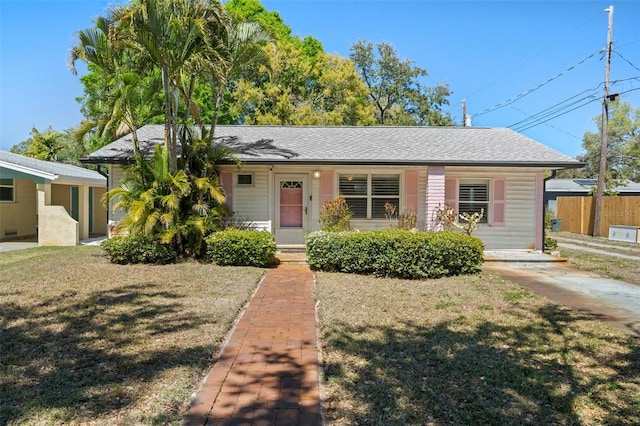 view of front facade featuring roof with shingles, a front yard, and fence