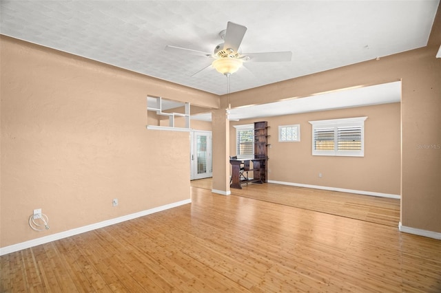 spare room featuring a ceiling fan, baseboards, and wood-type flooring