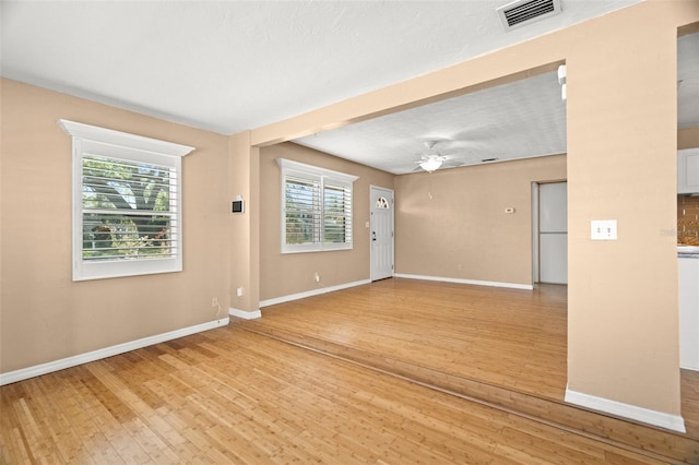 unfurnished room featuring baseboards, visible vents, light wood finished floors, and ceiling fan