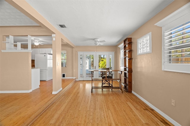 interior space with visible vents, light wood-style flooring, french doors, baseboards, and ceiling fan