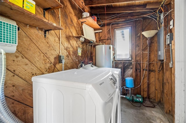 washroom with electric panel, wooden walls, water heater, and washer and clothes dryer