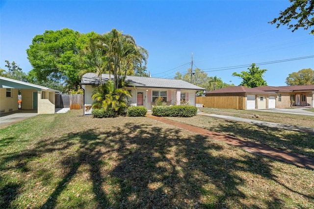 ranch-style home with a carport, a front lawn, and fence