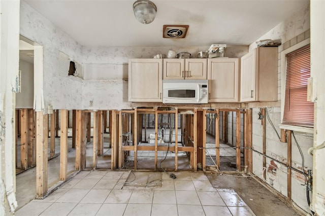 kitchen with light tile patterned floors, visible vents, white microwave, and light brown cabinets