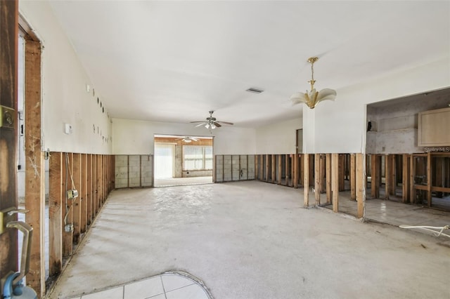 miscellaneous room featuring visible vents, unfinished concrete flooring, ceiling fan, and a wainscoted wall