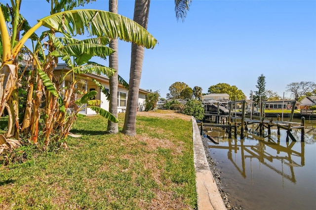 dock area with boat lift, a yard, and a water view