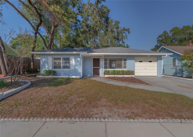 ranch-style home featuring a front lawn, fence, concrete driveway, stucco siding, and an attached garage