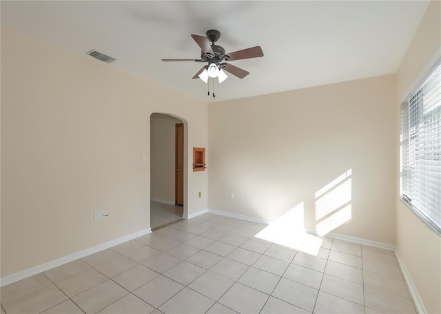 unfurnished room featuring a ceiling fan, light tile patterned floors, visible vents, and arched walkways