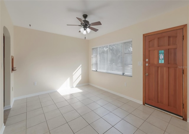 foyer entrance with light tile patterned floors, baseboards, arched walkways, and a ceiling fan