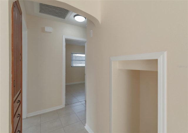 hallway featuring light tile patterned floors, visible vents, baseboards, and arched walkways