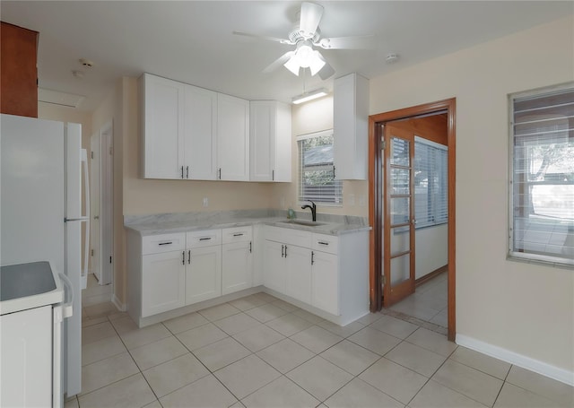 kitchen featuring a sink, white cabinetry, freestanding refrigerator, light tile patterned floors, and ceiling fan