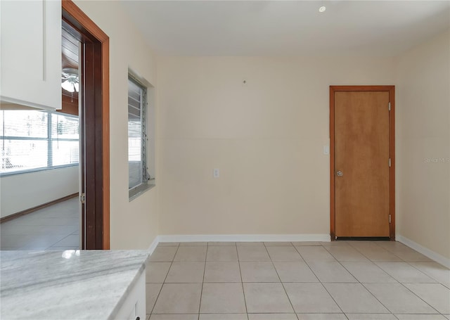 unfurnished room with light tile patterned flooring and baseboards