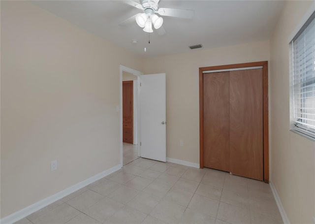 unfurnished bedroom featuring a ceiling fan, baseboards, visible vents, light tile patterned flooring, and a closet