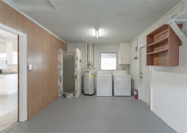 basement featuring washer and dryer, electric water heater, and wood walls