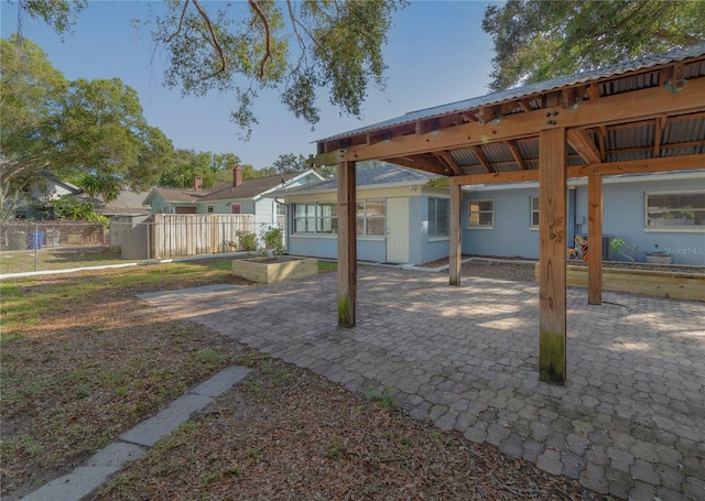 rear view of house with a patio area, metal roof, stucco siding, and fence