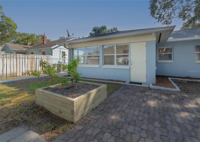 back of house with stucco siding, a vegetable garden, and fence