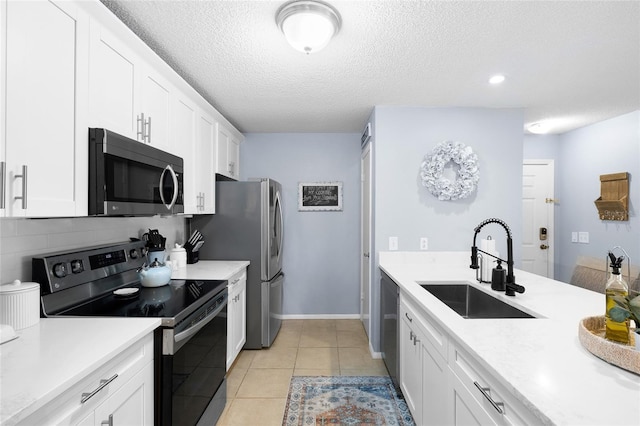 kitchen with light tile patterned flooring, stainless steel appliances, light countertops, and a sink