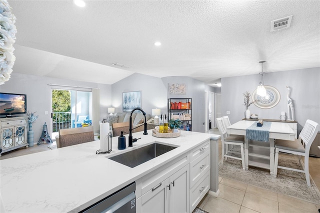 kitchen with open floor plan, white cabinets, visible vents, and a sink