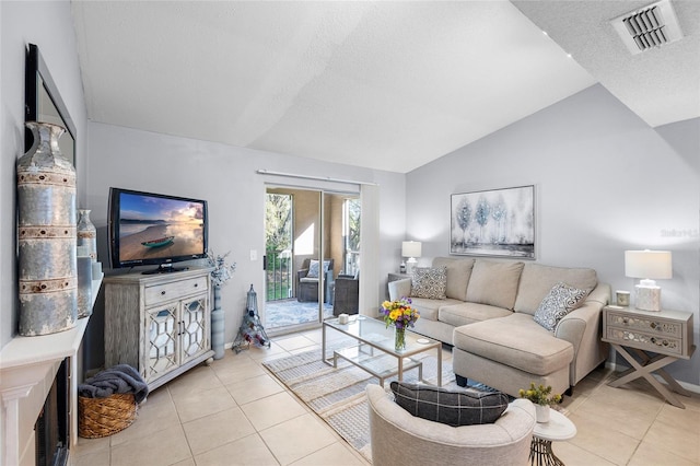 living area featuring visible vents, a textured ceiling, light tile patterned flooring, and vaulted ceiling