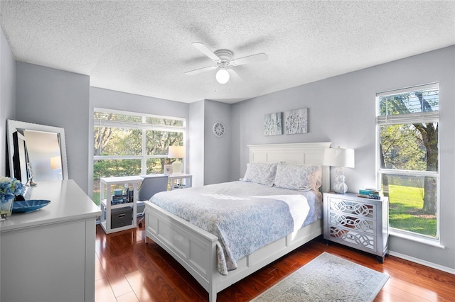 bedroom featuring a textured ceiling, dark wood-type flooring, and a ceiling fan