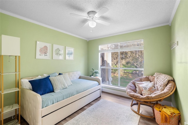 bedroom featuring ceiling fan, a textured ceiling, wood finished floors, and ornamental molding