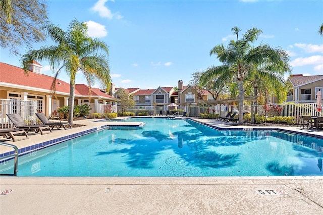 community pool featuring a patio, fence, and a residential view