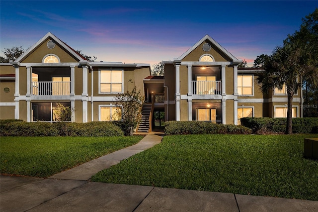 view of front of property with stucco siding, a yard, and stairway