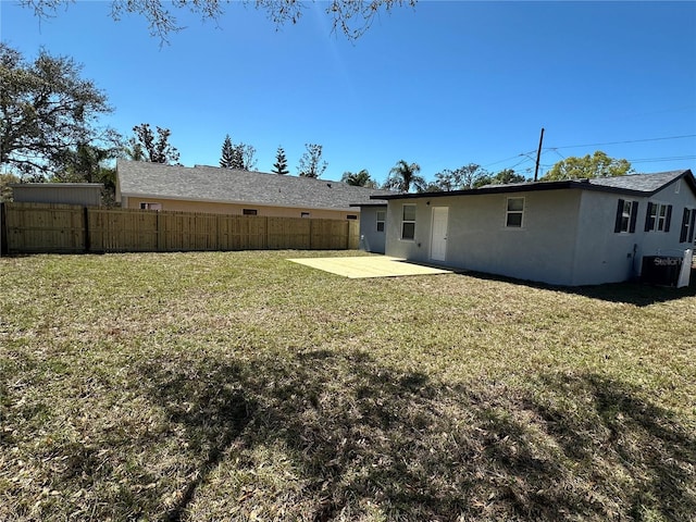 rear view of property featuring stucco siding, a lawn, a patio area, and fence