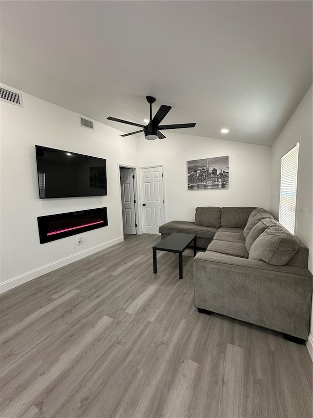 living area with visible vents, lofted ceiling, wood finished floors, and a fireplace