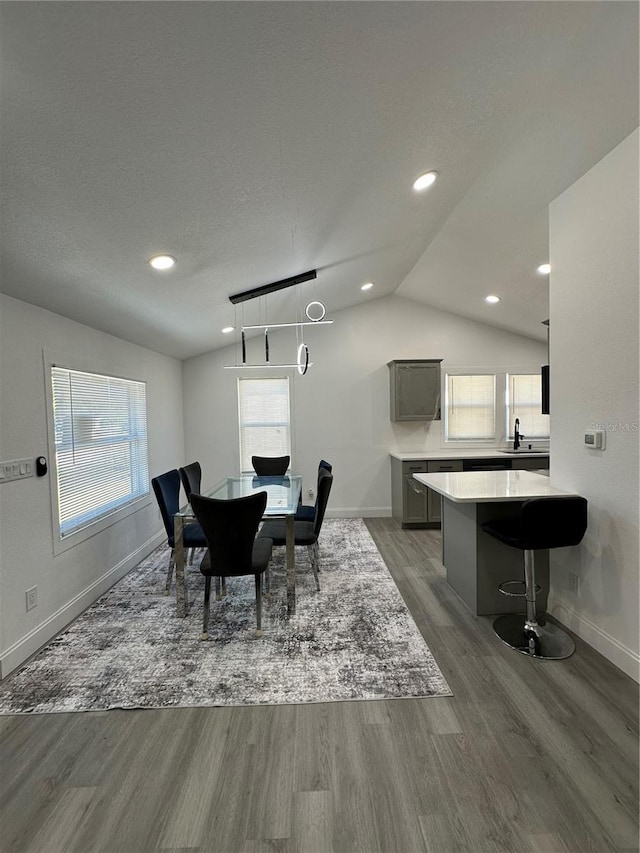 dining room with recessed lighting, baseboards, wood finished floors, and vaulted ceiling