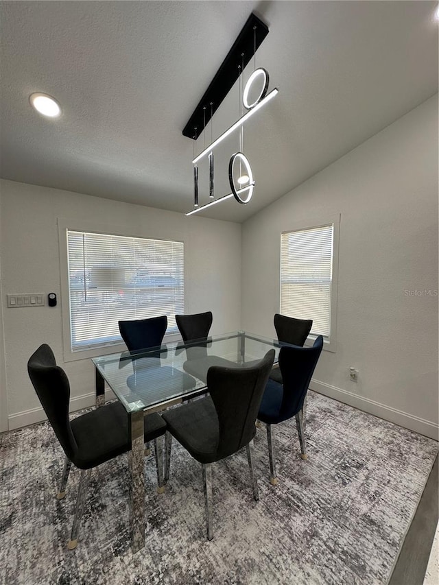 dining space featuring a textured ceiling, baseboards, lofted ceiling, and wood finished floors