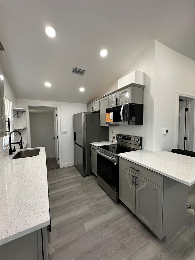 kitchen with visible vents, gray cabinets, appliances with stainless steel finishes, a peninsula, and a sink