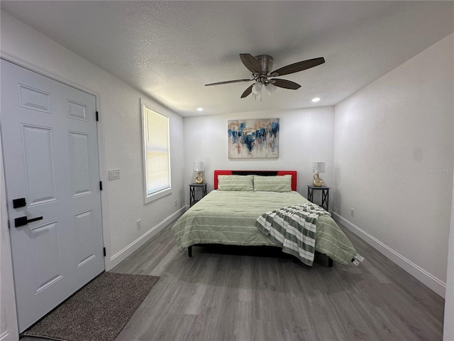 bedroom featuring ceiling fan, wood finished floors, baseboards, and a textured ceiling