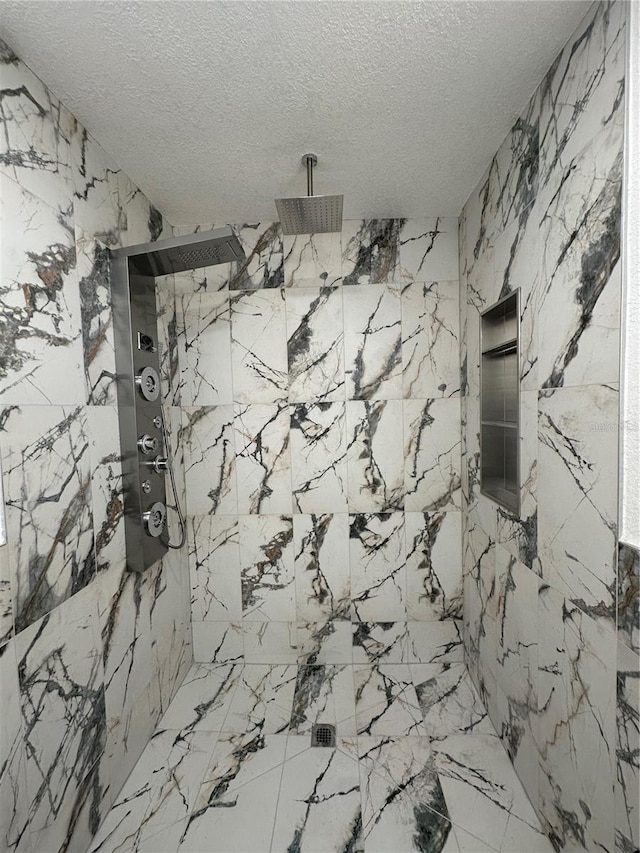 bathroom with stone wall, a marble finish shower, and a textured ceiling