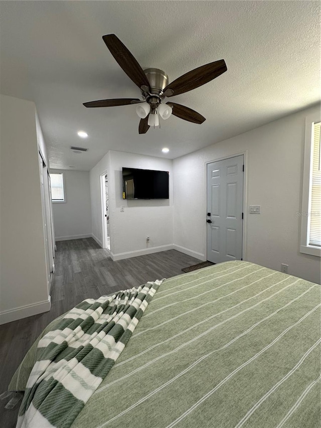 unfurnished bedroom featuring visible vents, baseboards, a textured ceiling, and dark wood finished floors