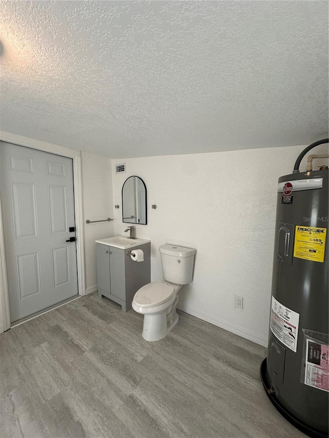 bathroom with vanity, wood finished floors, baseboards, a textured ceiling, and electric water heater