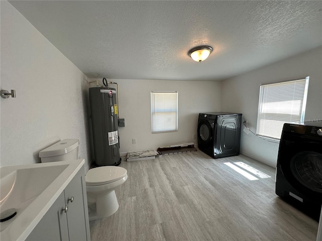 clothes washing area featuring light wood finished floors, laundry area, washer / clothes dryer, and electric water heater