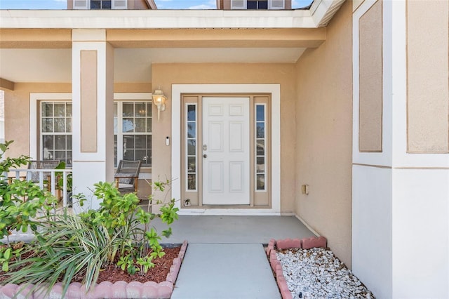 view of exterior entry featuring stucco siding and a porch