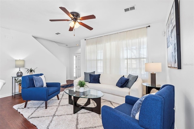 living area with visible vents, baseboards, wood finished floors, and a ceiling fan