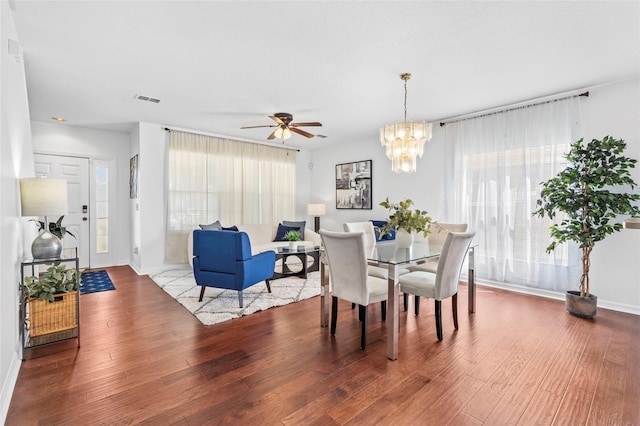 dining space featuring visible vents, ceiling fan with notable chandelier, baseboards, and wood finished floors