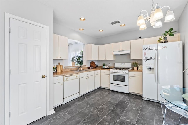 kitchen with white appliances, visible vents, a sink, under cabinet range hood, and a notable chandelier