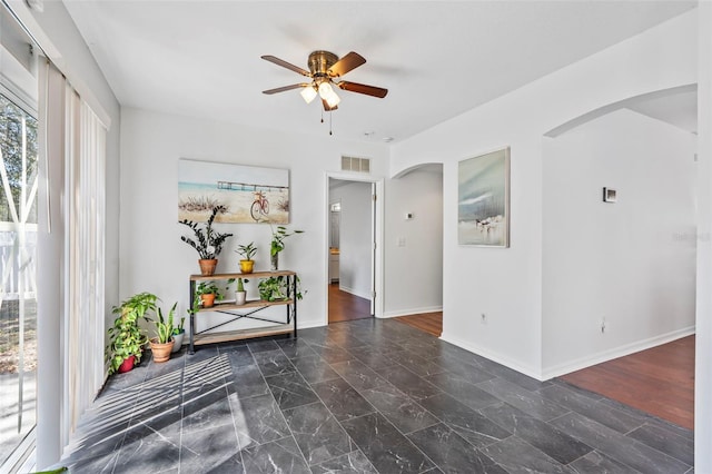 foyer featuring arched walkways, visible vents, baseboards, and ceiling fan