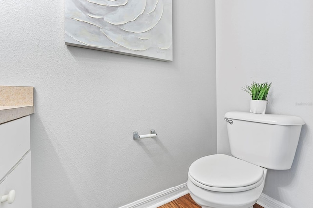 bathroom featuring vanity, toilet, wood finished floors, and baseboards