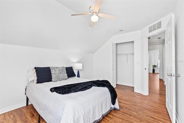 bedroom featuring visible vents, a ceiling fan, wood finished floors, a closet, and vaulted ceiling